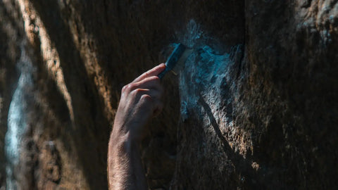 a person holding a cell phone up against a rock